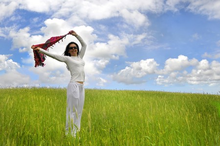 Woman posing in a green field with a scarfの写真素材