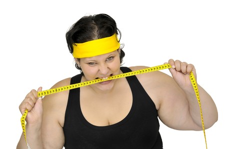 Angry large girl biting a measuring tape isolated in white