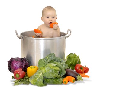 Beautiful young baby in a pan with vegetablesの写真素材