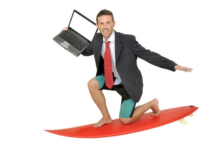 Young businessman with surf board and laptopの写真素材