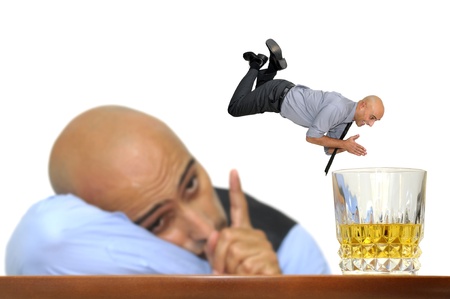 Businessman looking at himself diving into a glass of alcohol isolated in whiteの写真素材