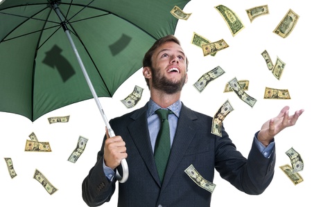 Young businessman with umbrella and money falling from the skyの写真素材