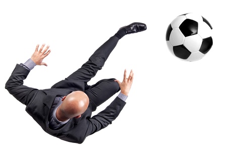 Businessman kicking a soccer ball isolated in whiteの写真素材