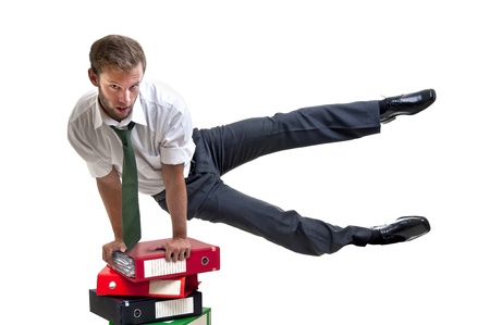 Businessman doing exercices over stack of filesの写真素材