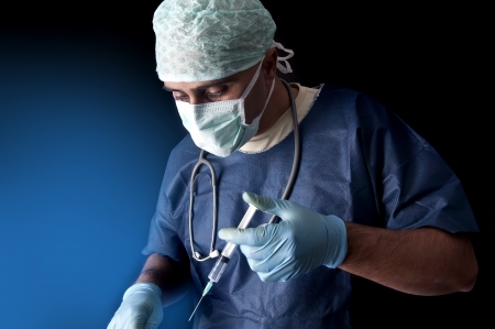 Doctor with syringe in a dark backgroundの写真素材