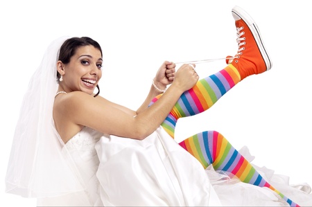 Funny bride with colorful socks putting orange shoesの写真素材