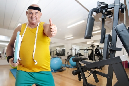 Large happy fitness man with weight scale in a gymの写真素材