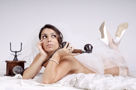 Beautiful bride in lingerie with phoneの写真素材