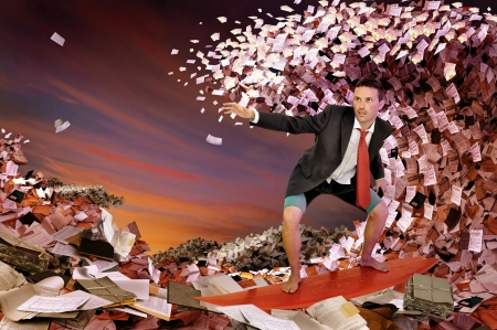 Businessman surfing in a sea made of files and papersの写真素材