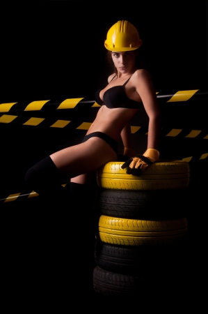 Sexy worker in lingerie posing against a dark background with tiresの写真素材
