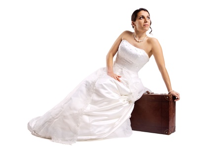 Beautiful bride posing with an old suitcase isolated in whiteの写真素材