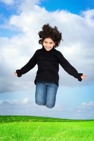 Young girl jumping in a green fieldの写真素材