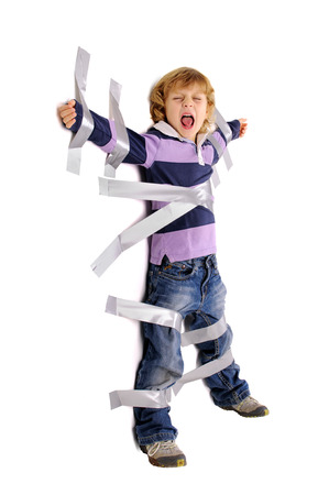 Young angry boy glued to the wall with duct tapeの写真素材