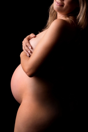 Beautiful nude pregnant woman isolated in blackの写真素材