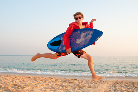 Handsome teen jumping in the beach with skimming boardの写真素材
