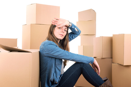 Beautiful tired girl with cardboard boxes unpacking in new home