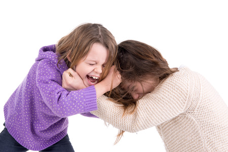 Young girls fighting, pulling hairs isolated in whiteの写真素材
