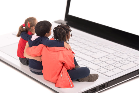 Group of young children in a laptop computer keyboard looking at the screen