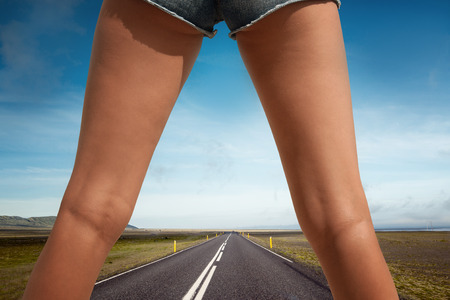 Woman's legs in the middle of an empty road in country sideの写真素材