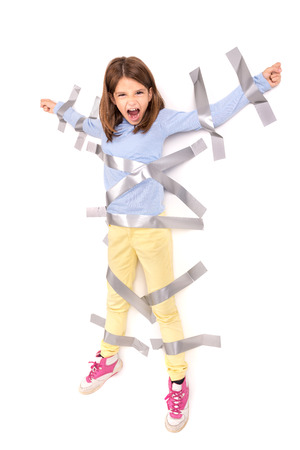Young girl tied to the wall with duct tapeの写真素材