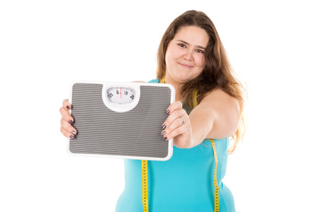 Beautiful large girl with measuring tape and weight scale isolated in whiteの写真素材