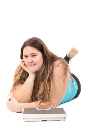 Beautiful large girl with a weight scale isolated in whiteの写真素材