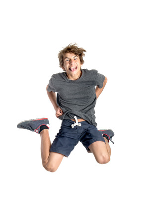 Teenage boy  doing funny acrobatic jumps isolated in whiteの写真素材