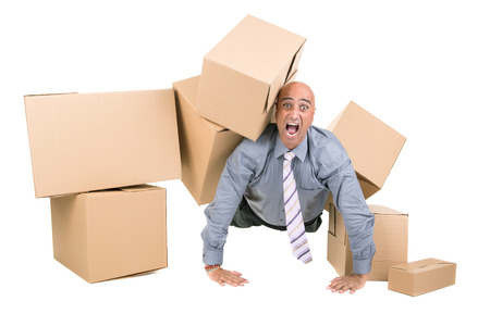 Stressed businessman under a pile of cardboard boxesの写真素材