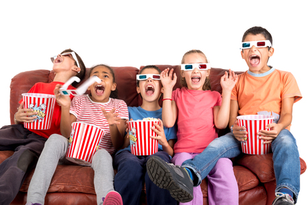 Group of children with 3d glasses and popcorn in a sofa having funの写真素材
