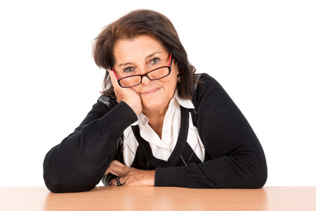 Beautiful senior woman with glasses at a desk isolated in whiteの写真素材
