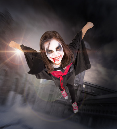 Girl with face-paint and Halloween vampire costume flyingの写真素材