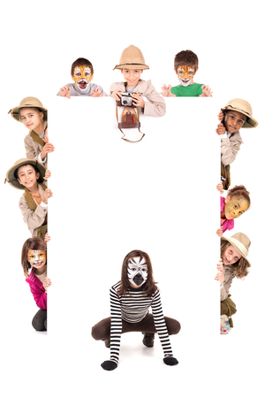 Children's group in safari clothes and animal face-paint over a white boardの写真素材