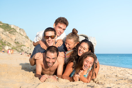 Group of happy teenage friends having fun at the beachの写真素材