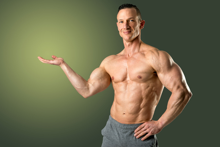 Powerful athletic man with great phisique with hand raised for product placement.の写真素材