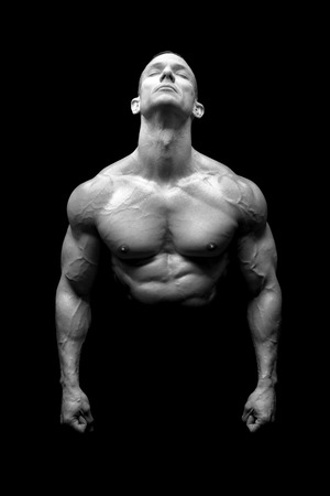 Power athletic man with great physique. Strong bodybuilder showing perfect body isolated in black.の写真素材