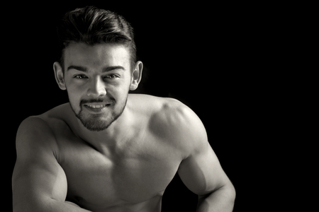 Handsome and muscular young man posing isolated in blackの写真素材