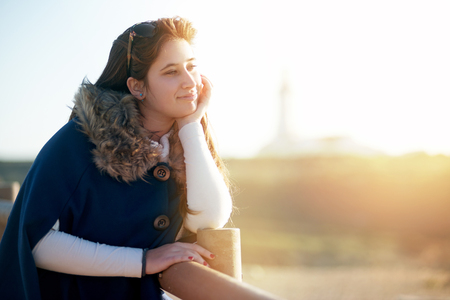 Beautiful happy young girl posing outdoors at sunset near a lighthouseの写真素材