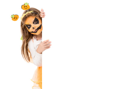 Girl with face-paint and Halloween pumpkin costume isolated in whiteの写真素材