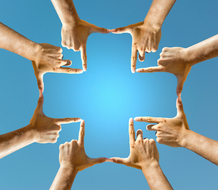 Hands forming a cross against the blue skyの写真素材
