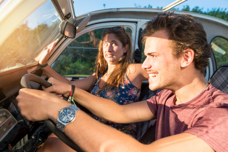 Couple in a car at sunset, with male driving fast and girl scared, screaming and praying.の写真素材