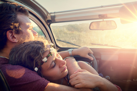 Happy young couple in a car enjoying the beautiful sunset in countryside.の写真素材