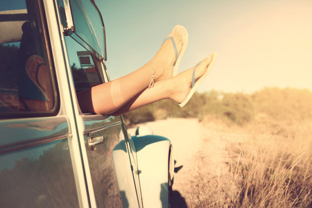 girl's legs in a retro car  at sunset, retro style.の写真素材
