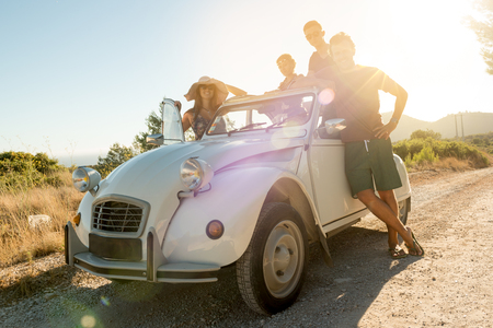 Group of happy people near a car in summertime, retro style.の写真素材