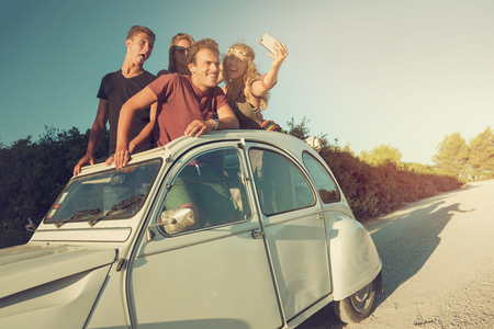 Group of happy people taking a selfie in a car at sunset in summer.の写真素材