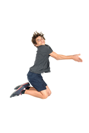 Teenage boy  doing funny acrobatic jumps isolated in whiteの写真素材
