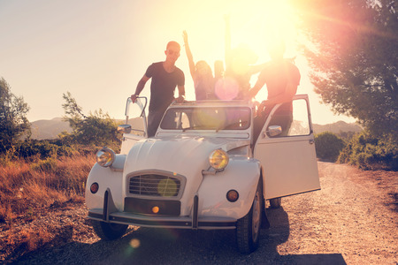 Group of happy people in a car at sunset in summer, ready for a roadtrip.の写真素材