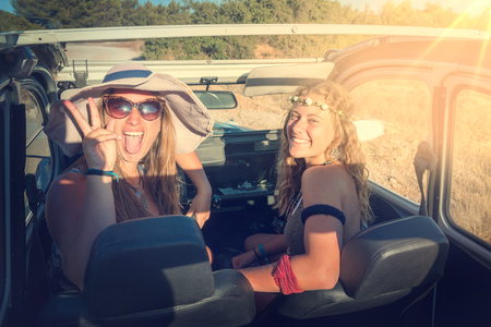 Retro image of girl friends in a car at sunsetの写真素材