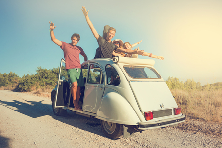Group of happy friends in a car at sunset in summer.の写真素材