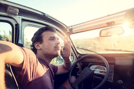 Stylish young man posing in a car, very retro look.の写真素材