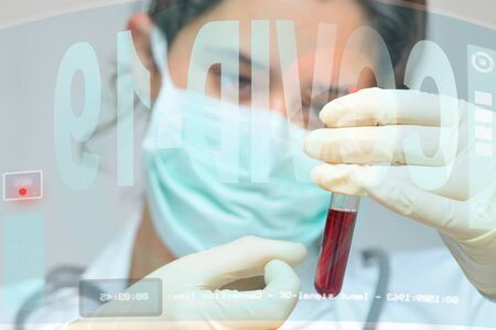 Young doctor analyzing a blood sample. Researching Corona virus cure, with digital screensの写真素材